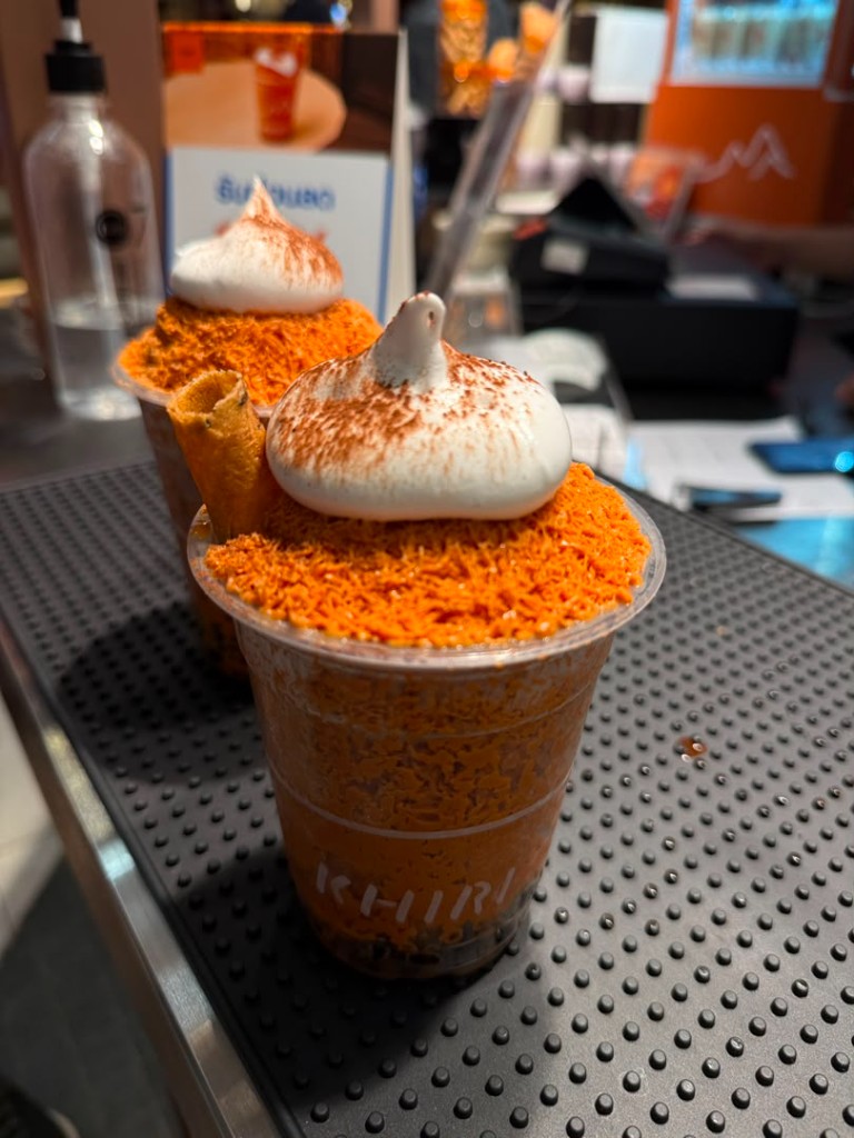 Two cups of KHIRI Thai tea with orange ice, cream, and toppings