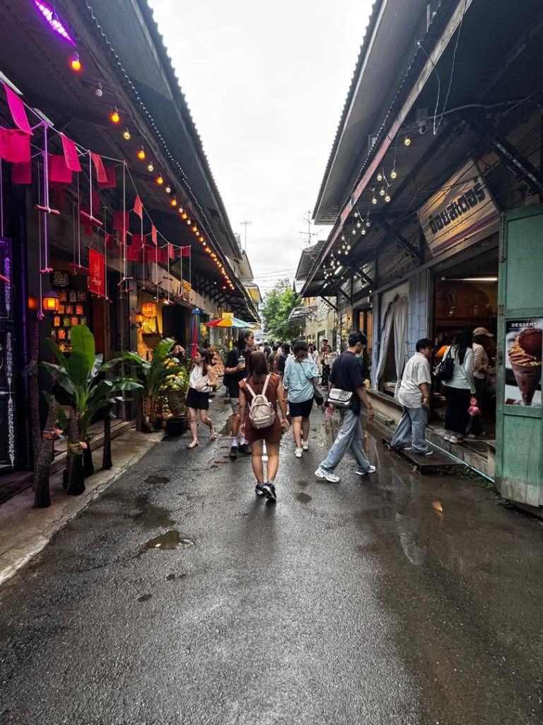 Narrow alley in Song Wat with shops, string lights, and wet pavement